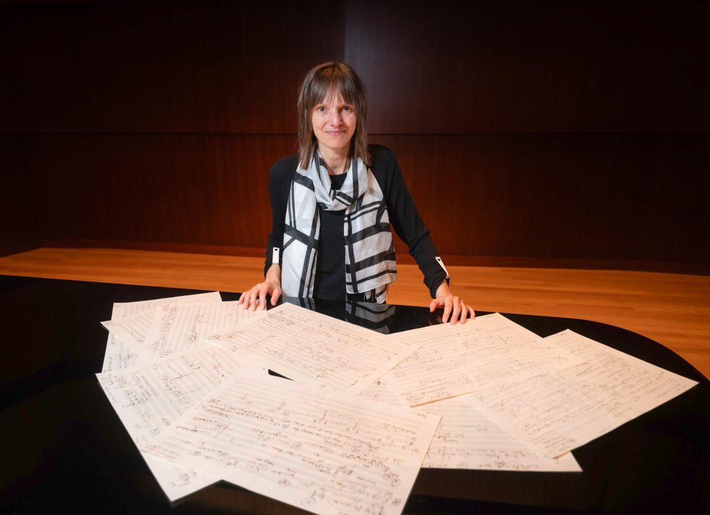 composer Ingrid Stölzel at a piano with score paper